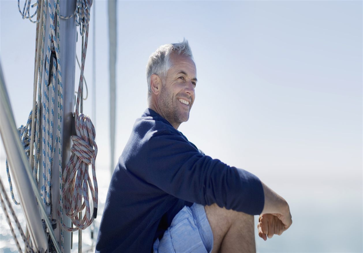 A man smiling and sitting on the deck of a sailing boat